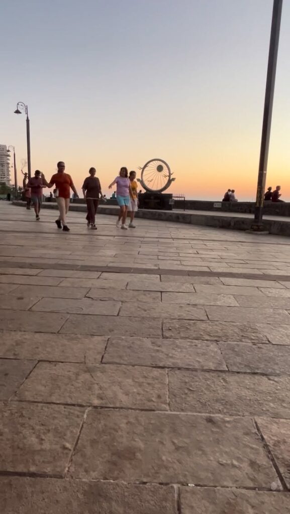Around me, life continues in its many forms. People walk past. Couples are lost in conversation. Some sit silently facing the sea, holding hands or thoughts. And in the midst of it all, I turn inward.